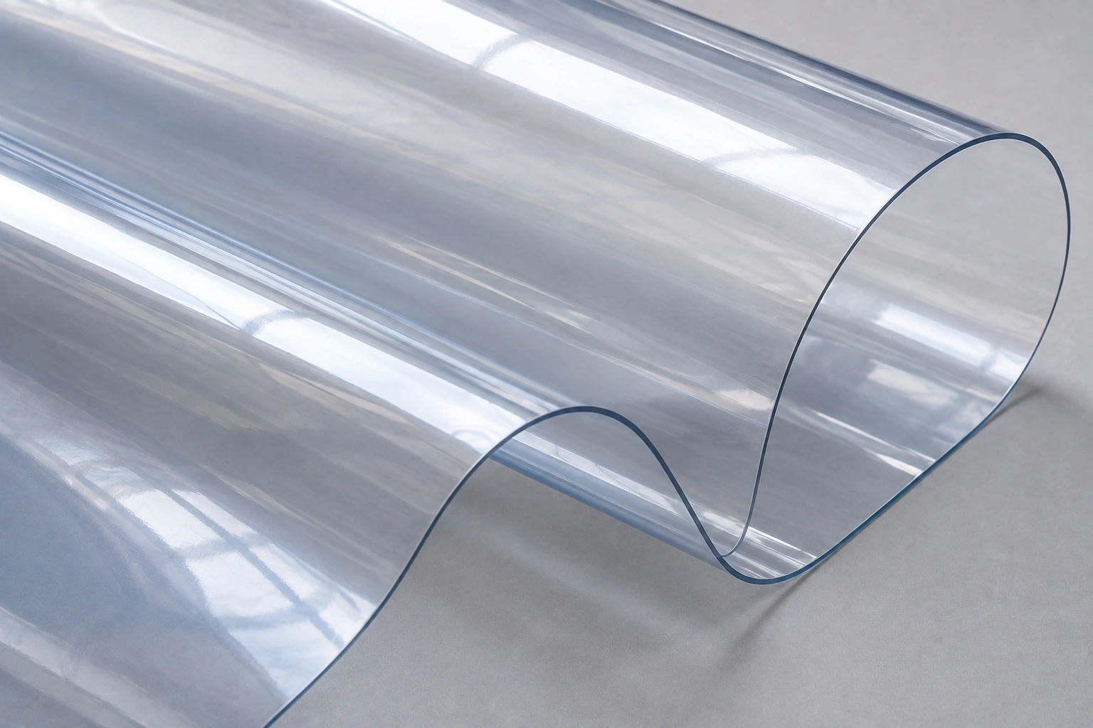 A thin sheet of highly transparent ETFE film flexing in a gentle wave, showing that it is clear and film-like rather than a woven fabric